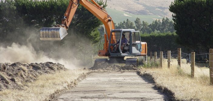 Photo of bulldozer tearing up grassland to make a road.