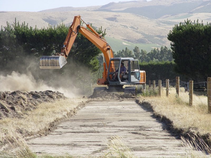 Photo of bulldozer tearing up grassland to make a road.