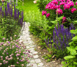 A pretty stone path with several kinds of flowers running along both sides of it.